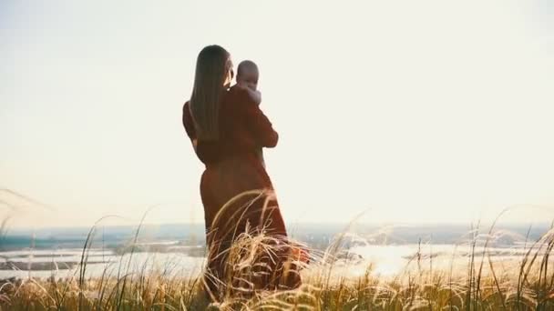 Женщина держит ребенка на руках. На фоне заката солнца.
. - Кадры, видео