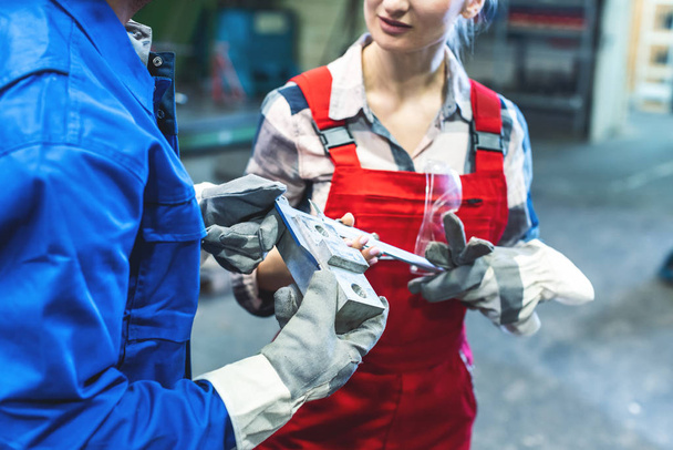 Kadın ve erkek işçi, metal işçiliği ölçümlerini kontrol ediyor. - Fotoğraf, Görsel