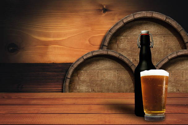 Houten vat achtergrond en glas bier op een oude eikenhouten tafel. - Foto, afbeelding
