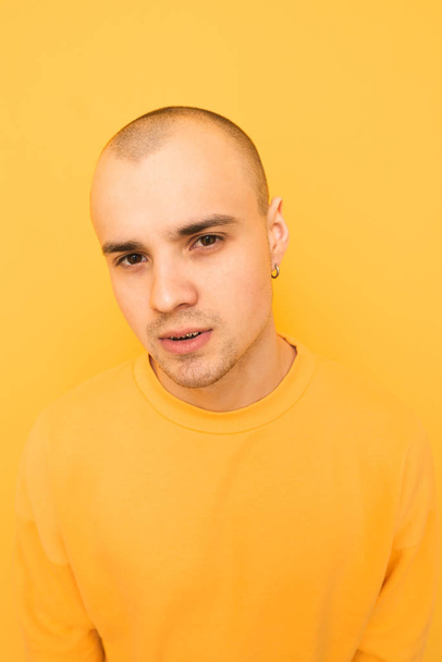 Πορτραίτο ενός κομψού τύπου με φαλακρό κεφάλι σε μια κίτρινη πλάτη - Φωτογραφία, εικόνα