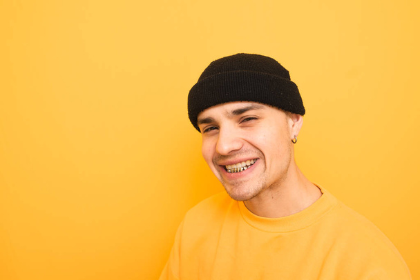 Feliz joven sonríe con una parrilla en los dientes, usando un sombrero
 - Foto, imagen