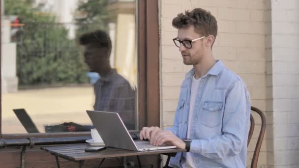 Online-Videochat von jungen Mann auf Laptop, sitzen im Freien - Filmmaterial, Video