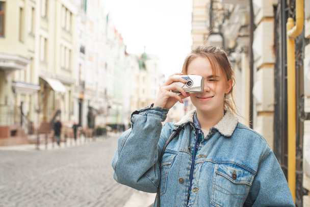 Portret van een toerist maakt een foto op een film camera in de straten van de stad, aantrekkelijk meisje lopen langs de straat van de Europese stad en maakt een foto. Analoge foto - Foto, afbeelding