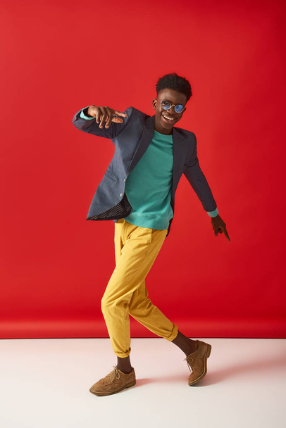 Positive young guy is dancing on red background - Photo, Image
