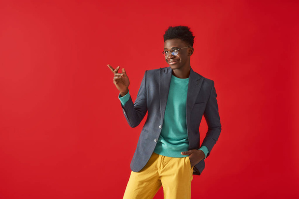 Stylish Afro American guy is posing on red background - Фото, зображення