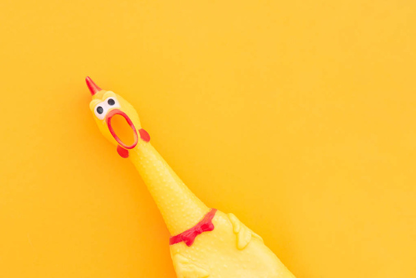 Creeping, rubber chicken toy on a pastel yellow background. Rubb - Foto, Bild