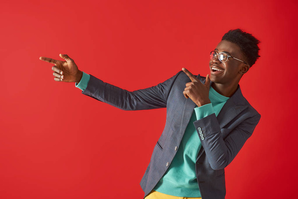 Happy Afro American man is posing on red background - Foto, imagen