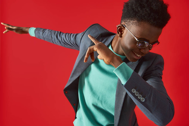 Cheerful Afro American man in glasses dancing on red background - Фото, зображення