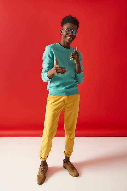 Positive Afro American guy is posing on red background - Фото, изображение
