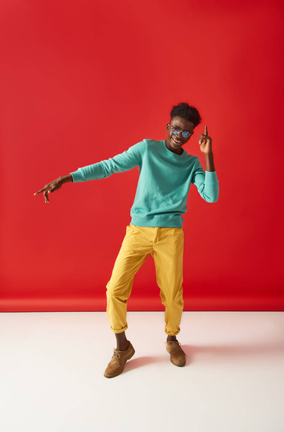 Positive guy in glasses is dancing on red background - Foto, Bild