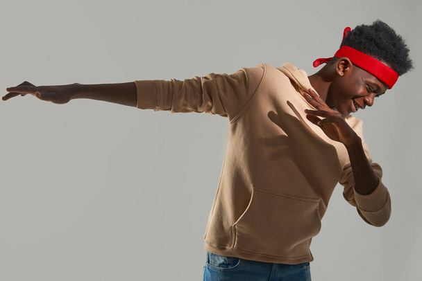 Cheerful Afro American man with red headband dancing on white background - Valokuva, kuva