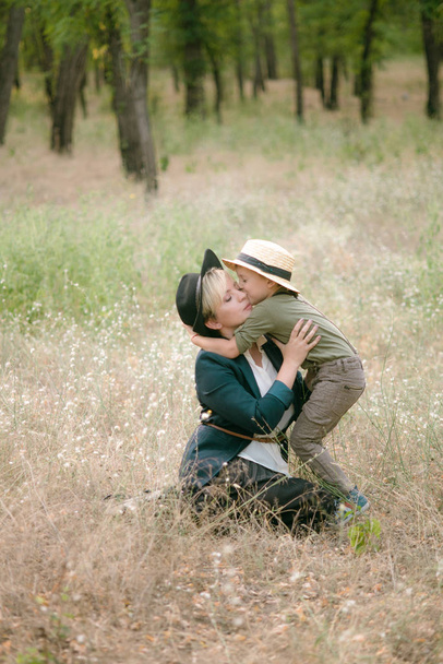 Little boy in a hat and his mom in the park in summer at sunset - 写真・画像