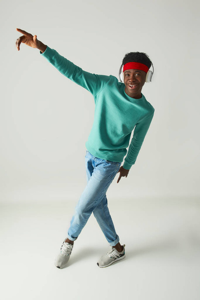 Cheerful young guy with red bandage is dancing - Foto, Bild