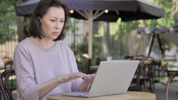 Mujer vieja con dolor de cabeza usando el ordenador portátil, sentado al aire libre
 - Imágenes, Vídeo