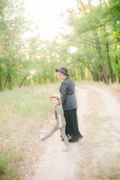 Little boy in a hat and his mom in the park in summer at sunset - Foto, immagini