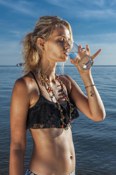 Beach vacation woman on holiday drinking fresh and clean water from glass for healthy hydration - Fotografie, Obrázek