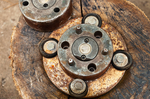 Vintage rusty mechanics with scratched copper gears and old round elements inside. Grungy copper and rusty metal textures on aged scratched wooden stump surface background. Rough brown backdrop  - Photo, Image