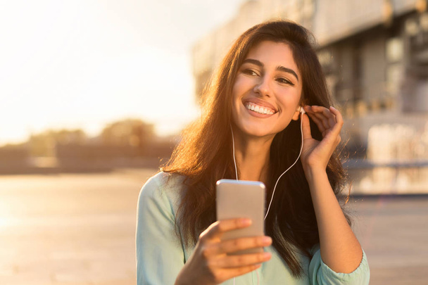 Calm evening. Woman listening music on phone, walking at sunset - Foto, imagen