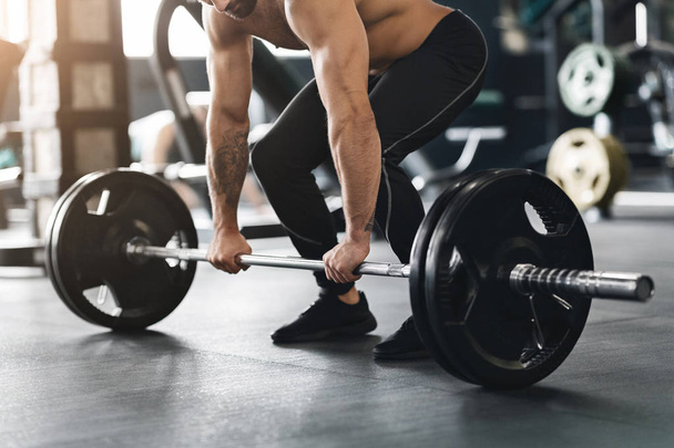 Haltérophilie musculaire soulevant haltère lourde du sol de la salle de gym
 - Photo, image