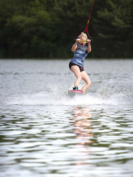 Young pretty slim woman riding wakeboard in summer - Photo, Image