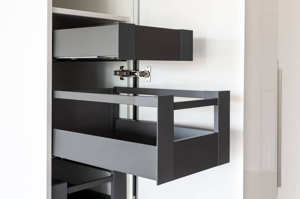 Armário de cozinha aberto com gavetas interiores em cores brancas e cinzentas
 - Foto, Imagem