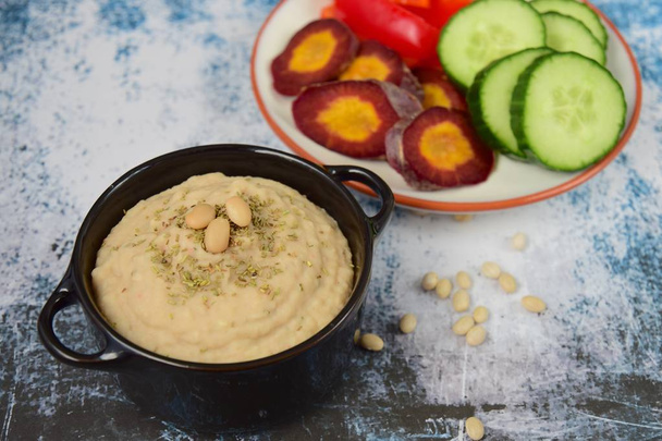 White bean hummus with red bell pepper sticks, sliced cucumber and purple carrot - Фото, изображение