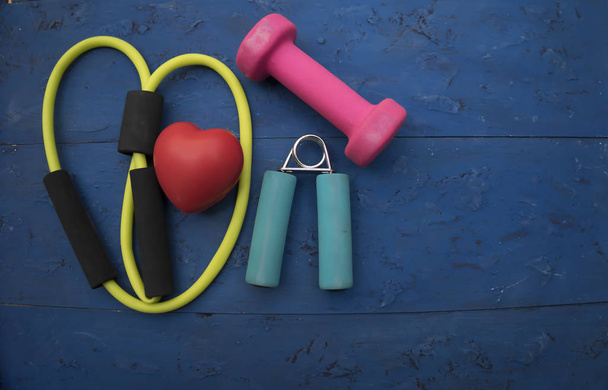 Zdrowy styl życia na serce sport dumbell sprzętu farbą niebieskim tle drewna. Zdrowa koncepcja - Zdjęcie, obraz