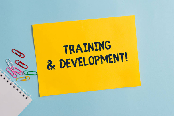 Text sign showing Training And Development. Conceptual photo Organize Additional Learning expedite Skills Plain cardboard and writing equipment placed above pastel colour backdrop. - Photo, Image
