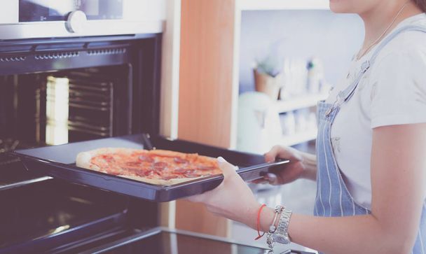 Happy young woman cooking pizza at home - Foto, afbeelding