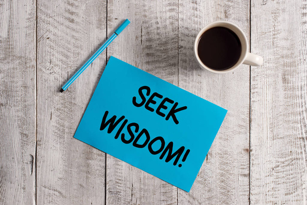 Conceptual hand writing showing Seek Wisdom. Business photo showcasing ability to think act using knowledge experience understanding Pastel Colour paper and pen with coffee cup on wooden table. - Photo, Image