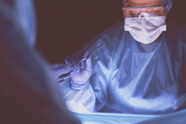 Cropped picture of scalpel taken doctors performing surgery. - Foto, Imagen