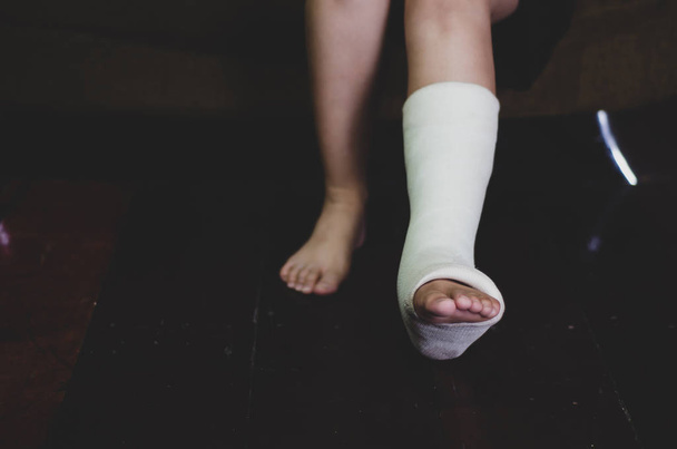  足の損傷の破れた傷を治療するための足首ストラップ。青い床に。足および足首の革紐は傷害から保護する。オブジェクトに焦点を当てないでください。ウォームトーン. - 写真・画像