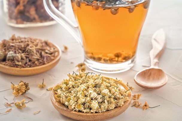 Herbal tea with pharmaceutical chamomile, dry chrysanthemum and hunters on a white table - Photo, Image