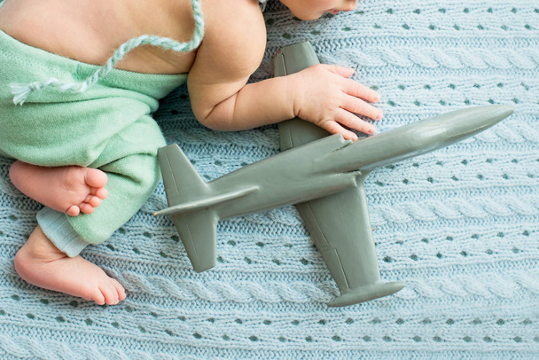 pasgeboren jongen met een speelgoed vliegtuig in zijn handen, kind met vliegtuig, luchtvaart  - Foto, afbeelding