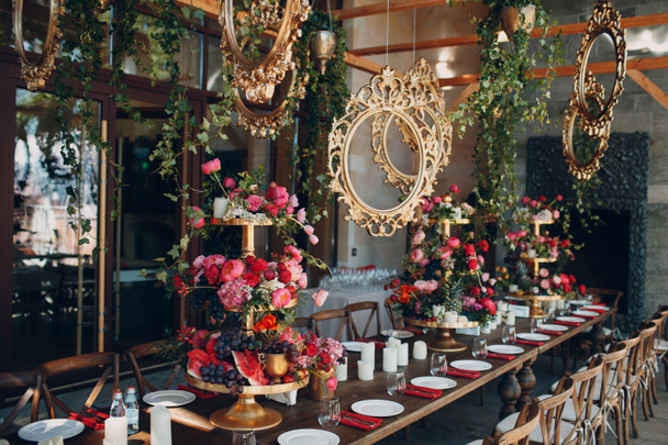 Bruiloft tafel bloemen met vruchten en bessen met goud handgemaakte decor in rood wit roze groene kleuren. - Foto, afbeelding