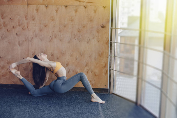 Молода приваблива дівчина робить фізичні вправи з йогою на підлозі на дерев'яному фоні
 - Фото, зображення