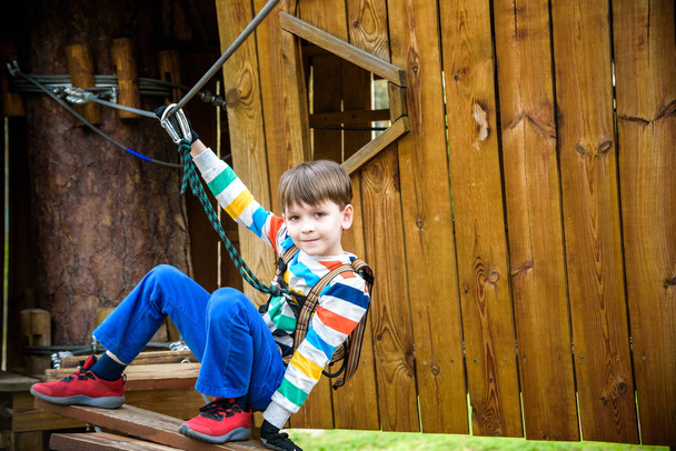 Un garçon grimpant dans une cabane dans les arbres. Jeux sains en plein air
. - Photo, image