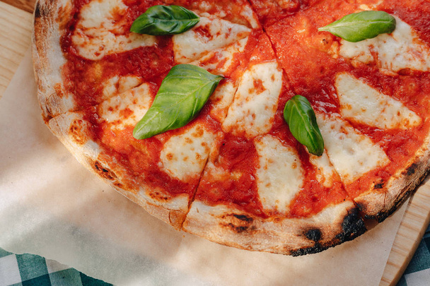 Неаполітанська піца з шинкою, сиром, руколою, базиліком, помідорами, посипаними сиром на дерев'яній дошці на скатертині в камері з місцем для тексту
 - Фото, зображення
