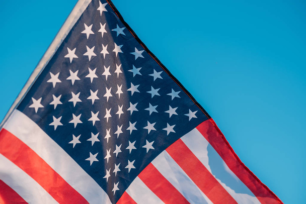 Amerykańska flaga na błękitnym niebie, bliska. Symbol niepodległości da - Zdjęcie, obraz