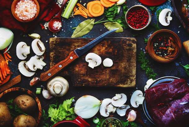 Fresh organic vegetables, ingredients, spices and meat for cooking soup on vintage kitchen table background with rustic wooden cutting board. Top view, place for text. Healthy cooking and eating concept - 写真・画像
