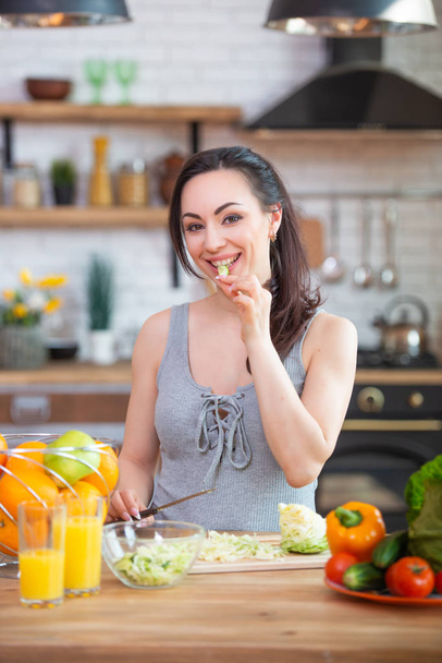 Aç bir kadın ellerini alır ve sebze yiyip ağzına doldurur. Sağlıklı gıda - Fotoğraf, Görsel