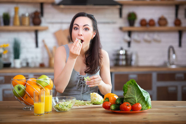 A hungry woman takes her hands and eats vegetables, stuffing them in her mouth. Healthy food - Foto, afbeelding