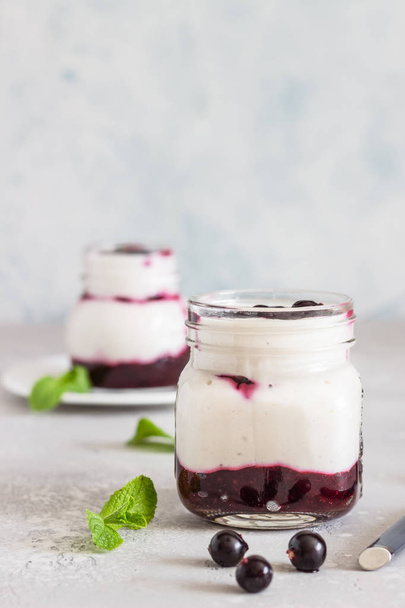 Jars of natural yogurt with berry sauce and mint on light grey table. Healthy eating. Copy space. Summer food concept.  - Valokuva, kuva