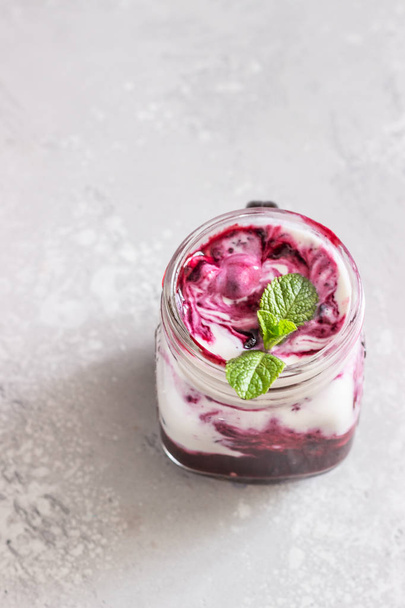 Jars of natural yogurt with berry sauce and mint on light grey table. Healthy eating. Copy space. Summer food concept.  - Zdjęcie, obraz