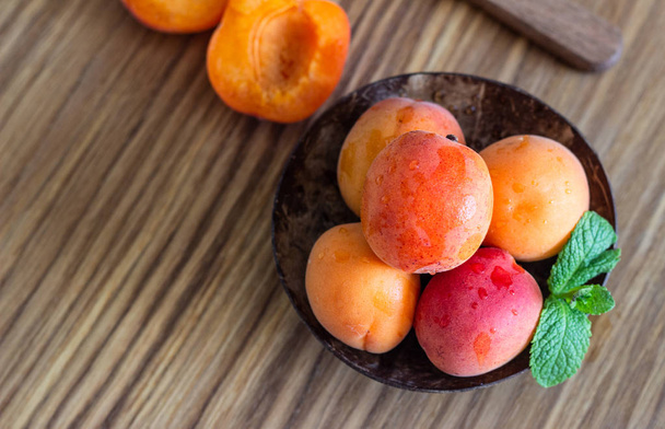 Delicious ripe apricots in a wooden bowl on a wooden cutting board.  - Photo, Image