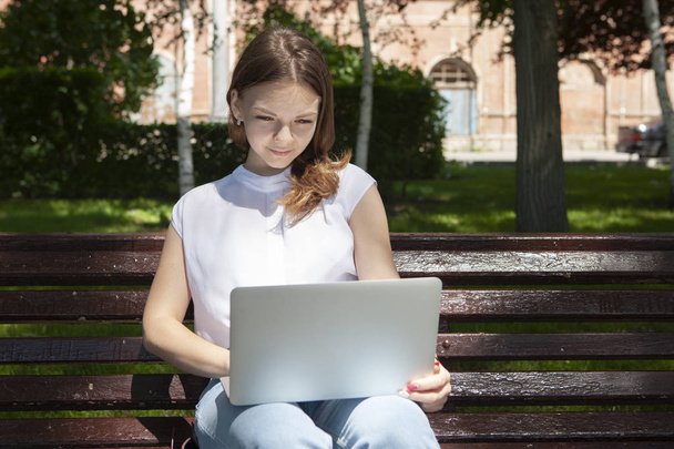 beautiful young student girl sitting on a bench with a laptop an - Foto, immagini