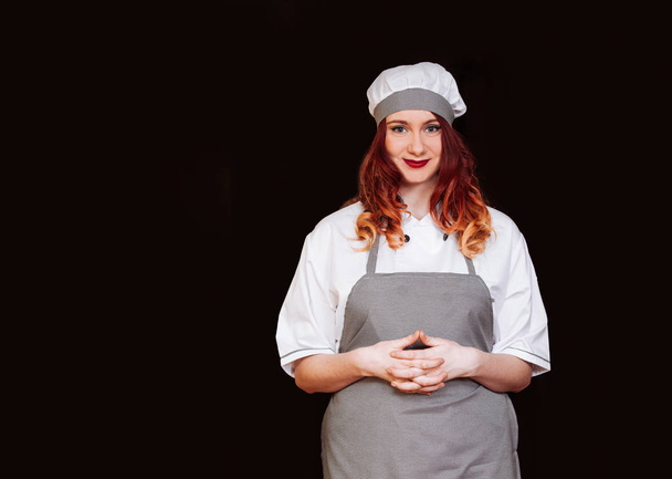 молодая шеф-повар женщина черная униформа изолированный белый фон фартук шляпа эмоция улыбка
 - Фото, изображение