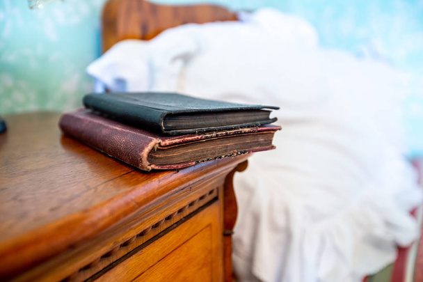 Libro cerrado sobre mesita de noche de madera cerca de la cama arrugada
 - Foto, Imagen
