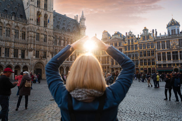 A nő áll a brüsszeli Grand Place-ban, Belgiumban naplementekor. - Fotó, kép