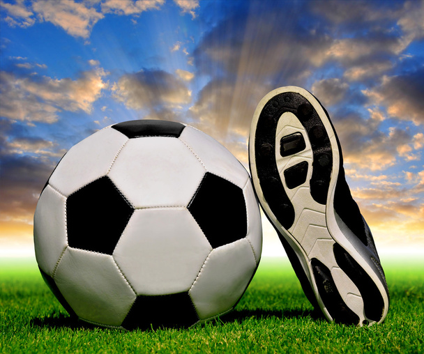 Футбольный мяч и обувь в траве
 - Фото, изображение
